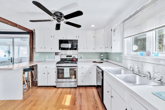 kitchen with sink, white cabinetry, light hardwood / wood-style flooring, and stainless steel gas range oven