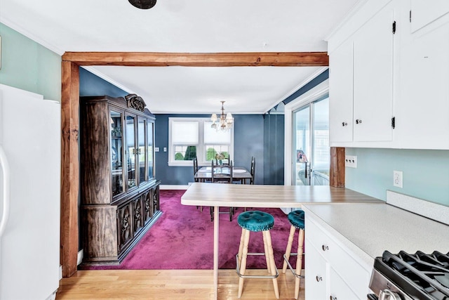 kitchen with white cabinets, decorative light fixtures, light hardwood / wood-style flooring, and white refrigerator