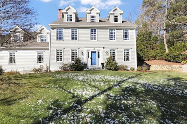 colonial home featuring entry steps, a front lawn, and roof with shingles