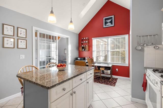 kitchen with gas range gas stove, hanging light fixtures, light tile patterned floors, a kitchen island, and white cabinets