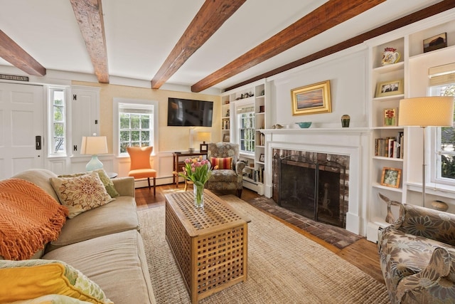 living room with wood finished floors, a fireplace, a baseboard heating unit, beamed ceiling, and a baseboard radiator