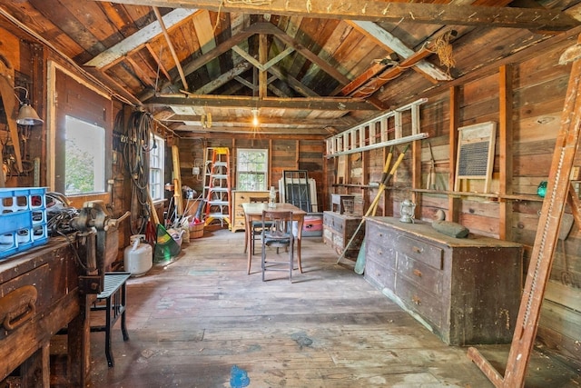 misc room featuring lofted ceiling, wood walls, and hardwood / wood-style floors