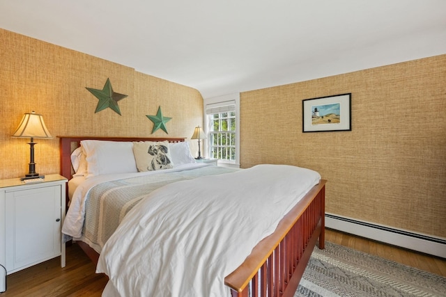 bedroom featuring wallpapered walls, wood finished floors, and a baseboard heating unit