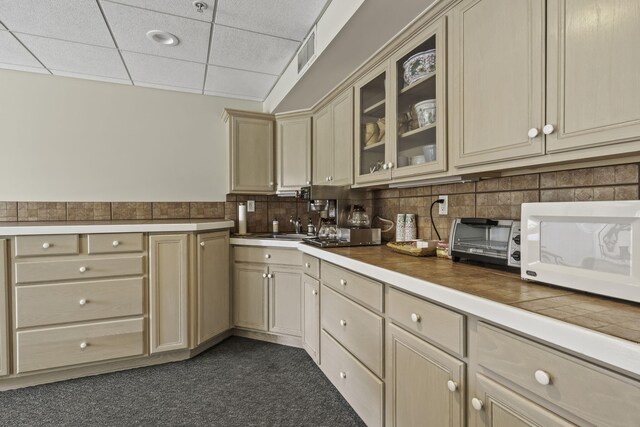 kitchen with sink, a drop ceiling, cream cabinets, and tasteful backsplash