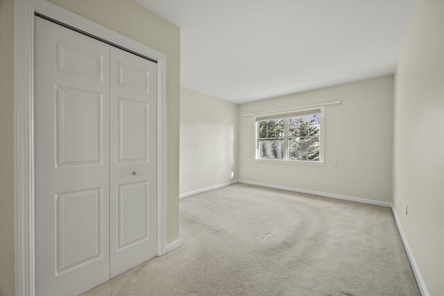 unfurnished bedroom featuring light carpet and a closet