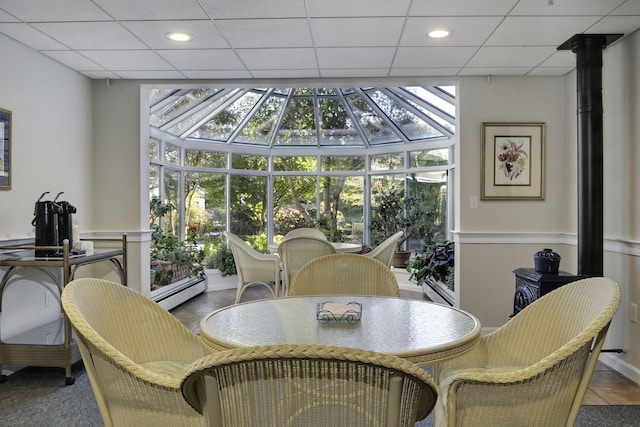 sunroom featuring a paneled ceiling, a wealth of natural light, and a baseboard heating unit