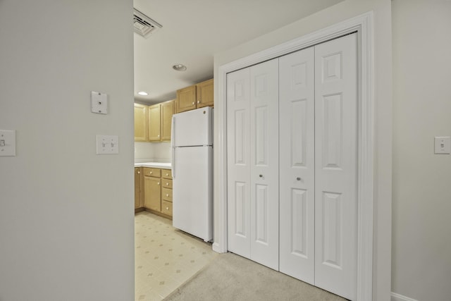 kitchen with light brown cabinets and white fridge