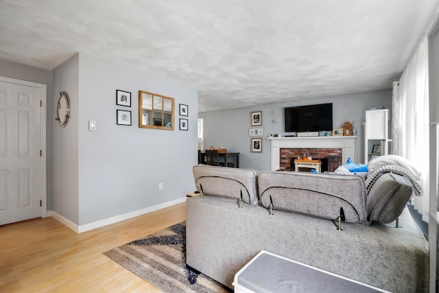 living room with a brick fireplace and wood-type flooring