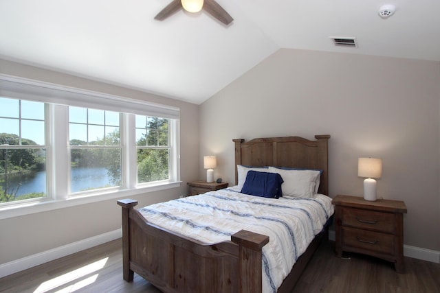 bedroom featuring a water view, dark hardwood / wood-style floors, vaulted ceiling, and ceiling fan