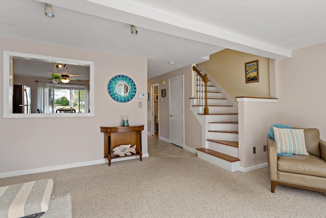 sitting room with carpet floors, baseboards, and stairs