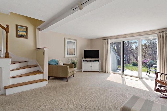 carpeted living area featuring stairs