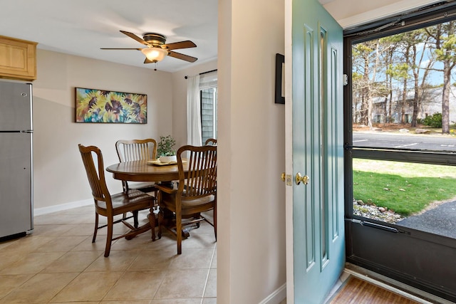 dining space with baseboards, a ceiling fan, and light tile patterned flooring