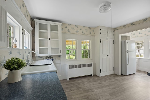 36 Uncle Barneys Rd, West Dennis, MA 02670 - kitchen featuring radiator heating unit, freestanding refrigerator, a sink, wallpapered walls, and light wood finished floors