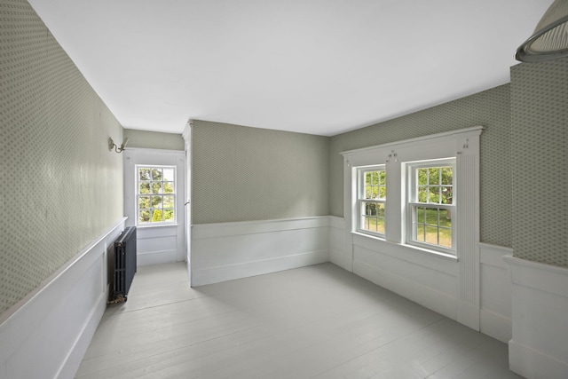 36 Uncle Barneys Rd, West Dennis, MA 02670 - spare room with a wainscoted wall, radiator heating unit, light wood finished floors, and wallpapered walls