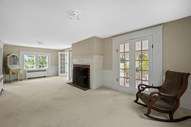 36 Uncle Barneys Rd, West Dennis, MA 02670 - living room with radiator, french doors, a wainscoted wall, carpet, and a brick fireplace
