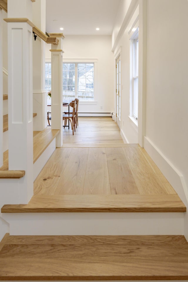 hallway with a baseboard heating unit and wood-type flooring