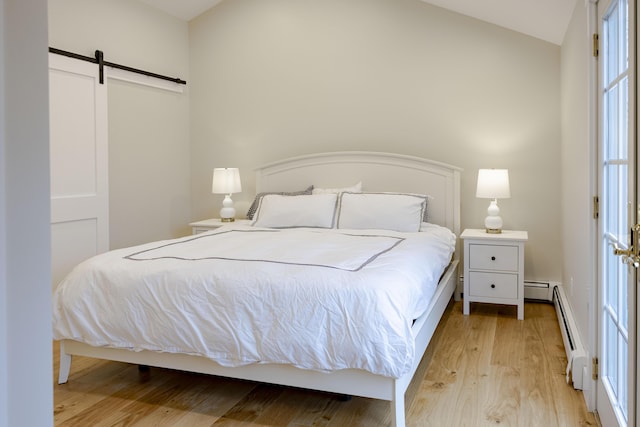 bedroom with a baseboard radiator, a barn door, and light hardwood / wood-style flooring