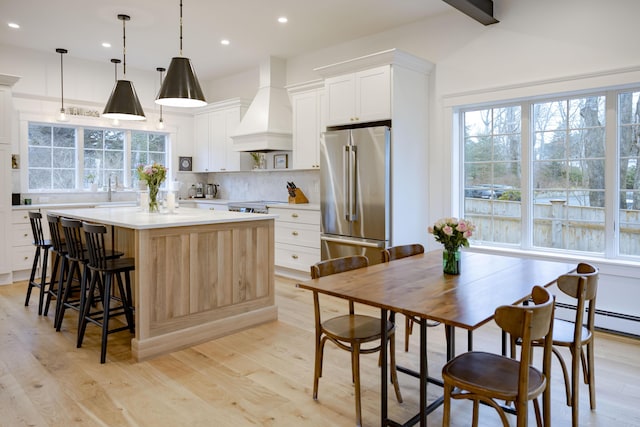 kitchen with white cabinetry, premium range hood, hanging light fixtures, and high end refrigerator