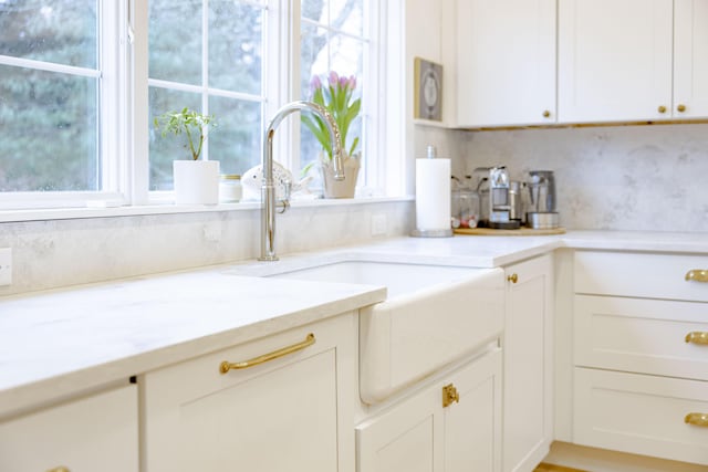 kitchen featuring light stone counters, sink, decorative backsplash, and white cabinets