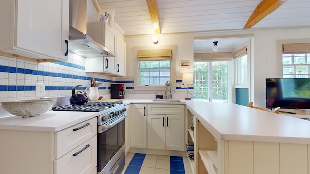 kitchen featuring wall chimney range hood, kitchen peninsula, and gas stove