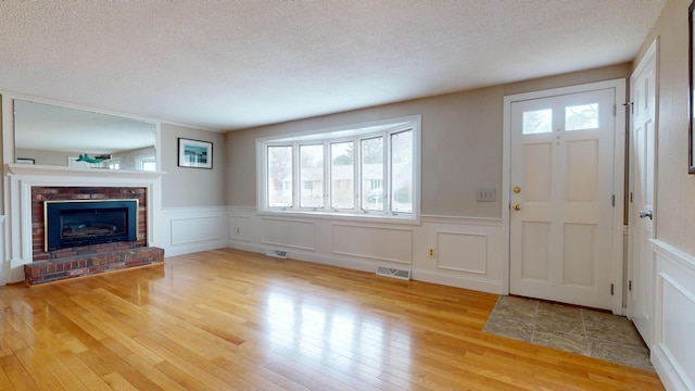 entrance foyer featuring light wood-type flooring, a textured ceiling, and a fireplace