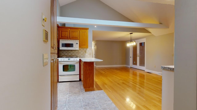 kitchen with a kitchen breakfast bar, pendant lighting, white appliances, decorative backsplash, and lofted ceiling