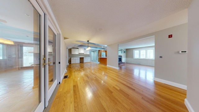 unfurnished living room with light hardwood / wood-style floors and a textured ceiling