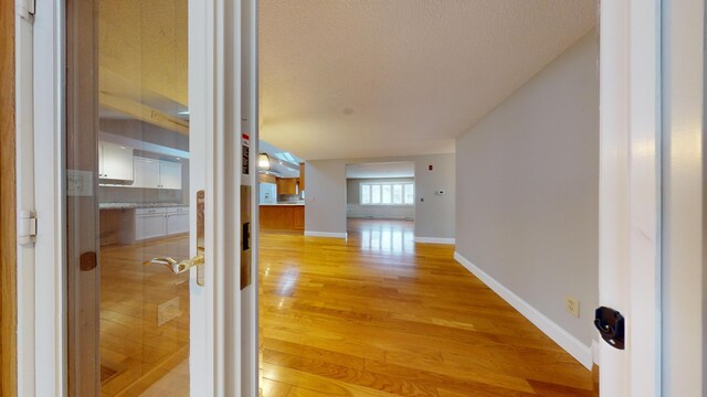 hall featuring light hardwood / wood-style floors and a textured ceiling