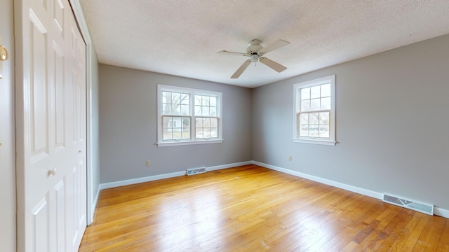 unfurnished bedroom featuring ceiling fan, a textured ceiling, a closet, and light wood-type flooring