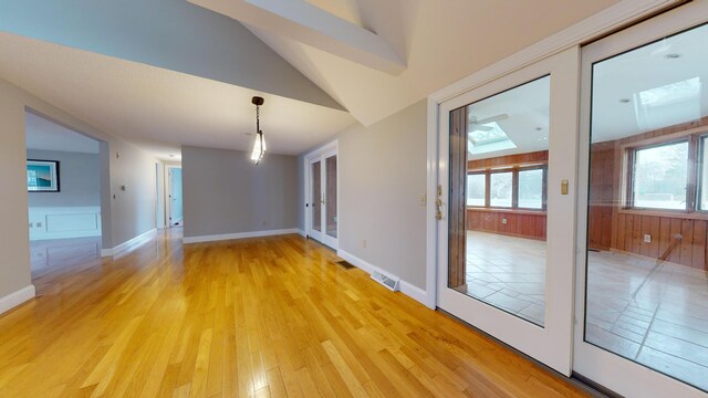 empty room with light hardwood / wood-style flooring and vaulted ceiling