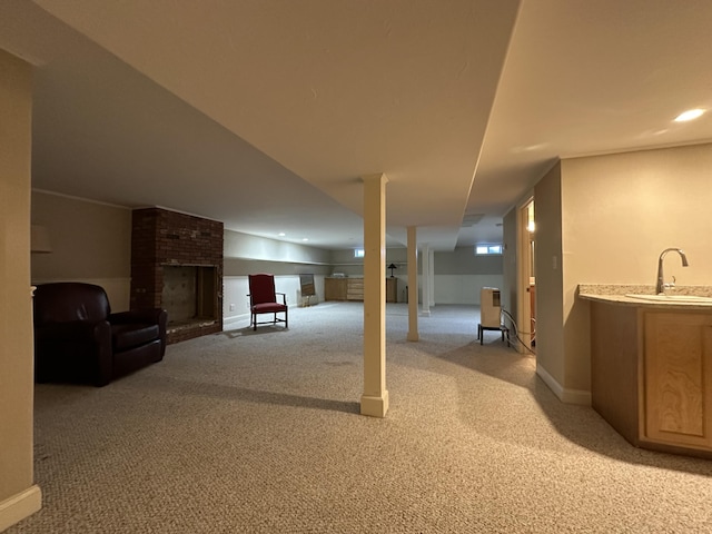 basement with sink, light carpet, and a fireplace