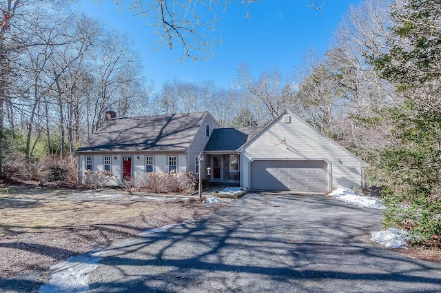 view of front of property featuring a garage, aphalt driveway, and a chimney