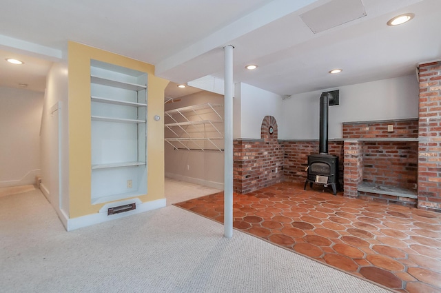 finished below grade area featuring baseboards, recessed lighting, a wood stove, and built in features