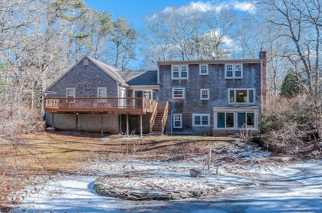 snow covered property with stairs, a chimney, and a deck