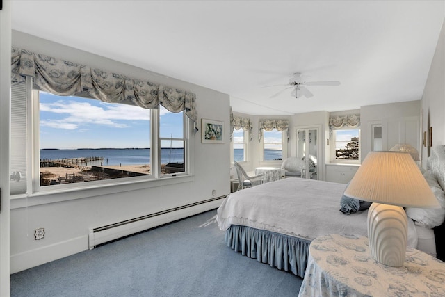 carpeted bedroom with ceiling fan, a water view, and a baseboard heating unit