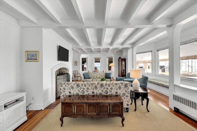 bedroom featuring light wood-type flooring, radiator, beamed ceiling, and coffered ceiling