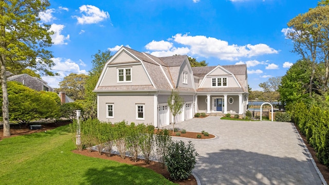 64 Pershing Ln, Orleans, MA 02653 - shingle-style home with a gambrel roof, a front lawn, decorative driveway, covered porch, and a garage