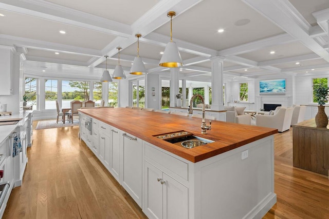 64 Pershing Ln, Orleans, MA 02653 - kitchen with butcher block counters, a sink, coffered ceiling, healthy amount of natural light, and white cabinets