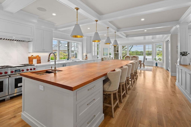 64 Pershing Ln, Orleans, MA 02653 - kitchen with butcher block counters, double oven range, a sink, a kitchen island with sink, and beam ceiling