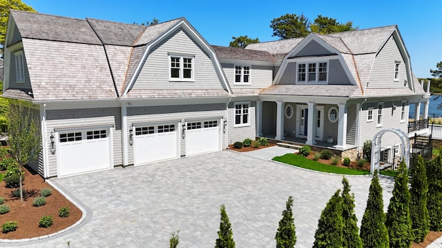 64 Pershing Ln, Orleans, MA 02653 - shingle-style home with a gambrel roof, covered porch, decorative driveway, and an attached garage