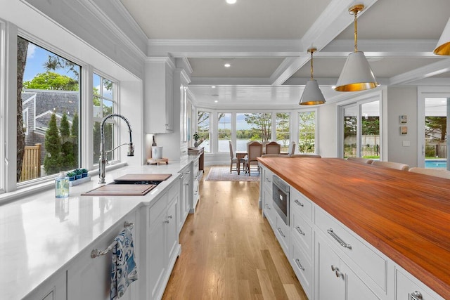 64 Pershing Ln, Orleans, MA 02653 - kitchen featuring wood counters, a sink, stainless steel microwave, plenty of natural light, and beamed ceiling