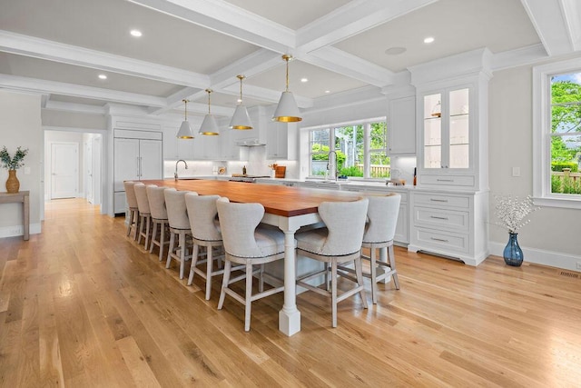 64 Pershing Ln, Orleans, MA 02653 - kitchen featuring butcher block countertops, beam ceiling, a kitchen bar, white cabinetry, and a sink