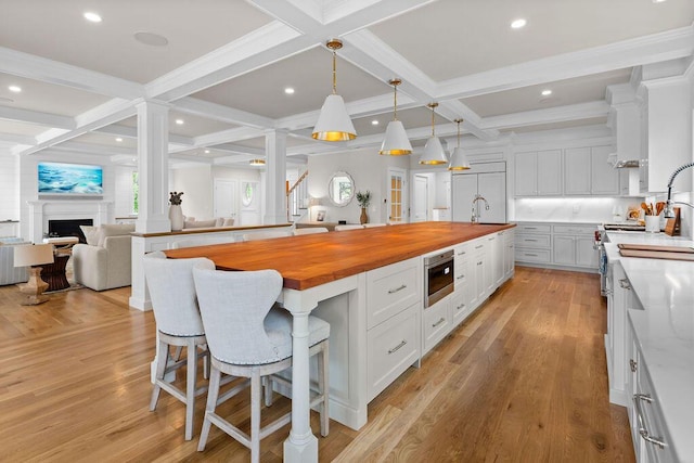 64 Pershing Ln, Orleans, MA 02653 - kitchen featuring butcher block counters, coffered ceiling, a sink, white cabinets, and a kitchen bar