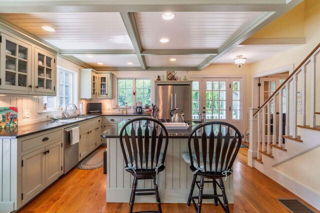 kitchen with light hardwood / wood-style flooring, sink, beam ceiling, a center island, and stainless steel appliances