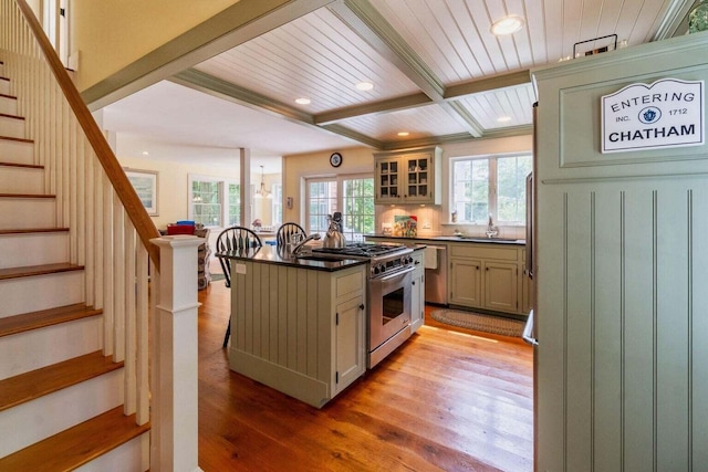 kitchen featuring dark countertops, a kitchen island, beamed ceiling, high end stainless steel range, and light wood-type flooring