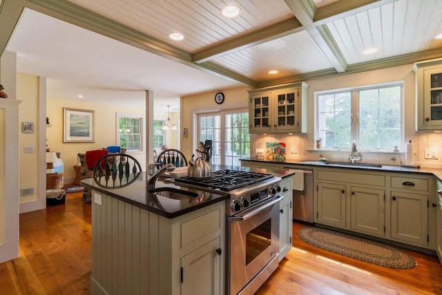 kitchen with a healthy amount of sunlight, a kitchen island, a sink, light wood finished floors, and stainless steel appliances