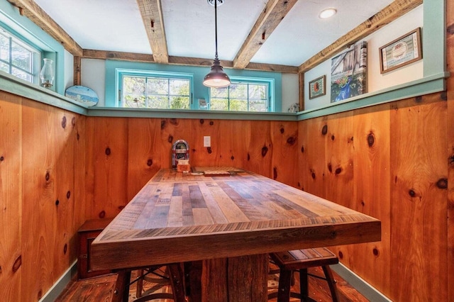 dining area with wood walls and beam ceiling