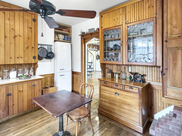 kitchen featuring wooden walls, ceiling fan, and light wood-type flooring