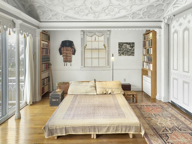 bedroom with crown molding, wood-type flooring, and multiple windows