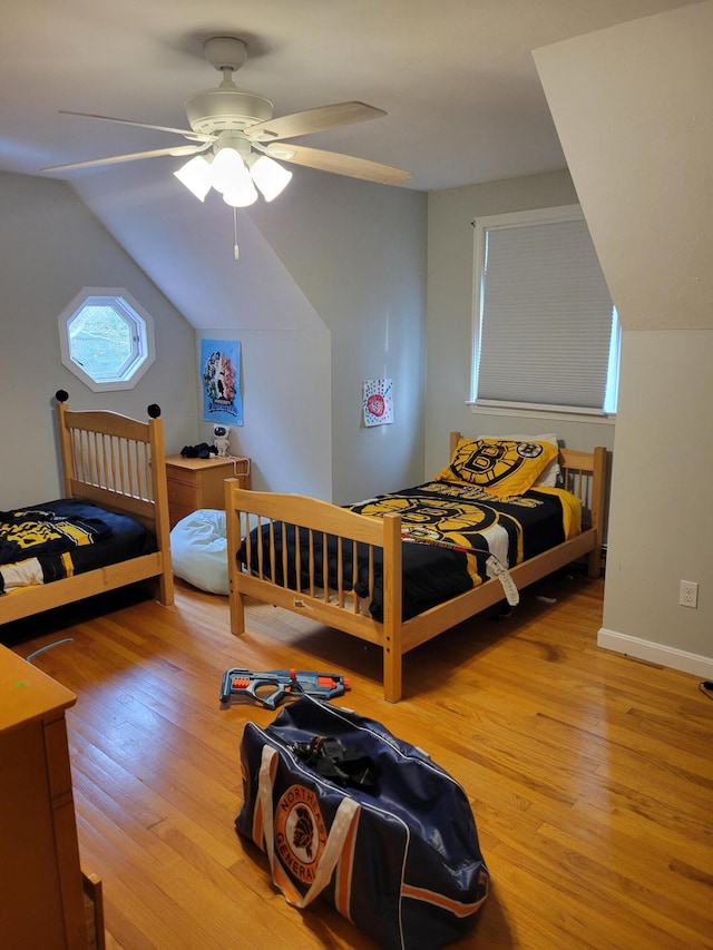 bedroom featuring light wood finished floors, ceiling fan, baseboards, and vaulted ceiling